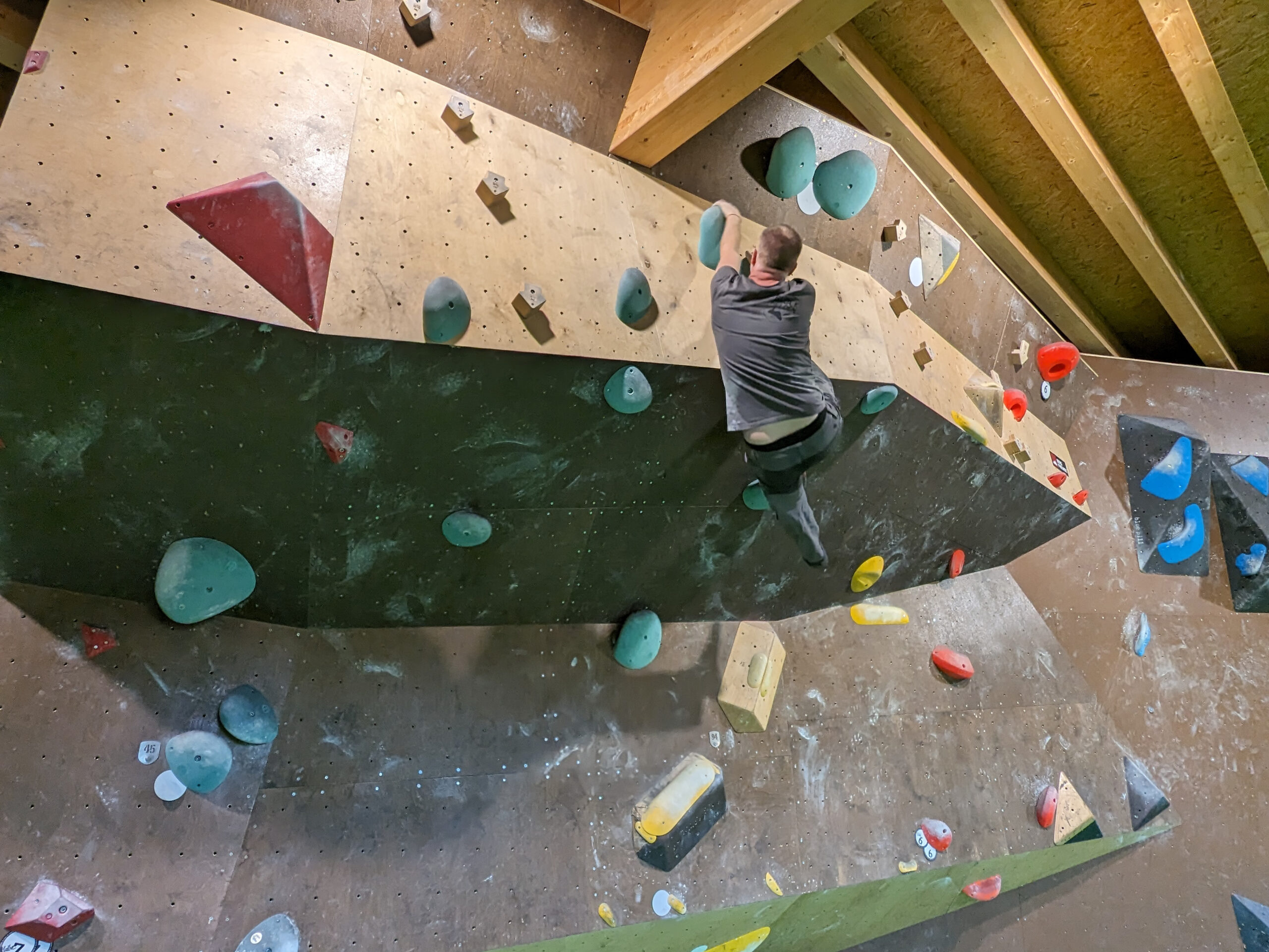Ein Mann klettert ohne Sicherung an einer Kletterwand in einer Boulderhalle.