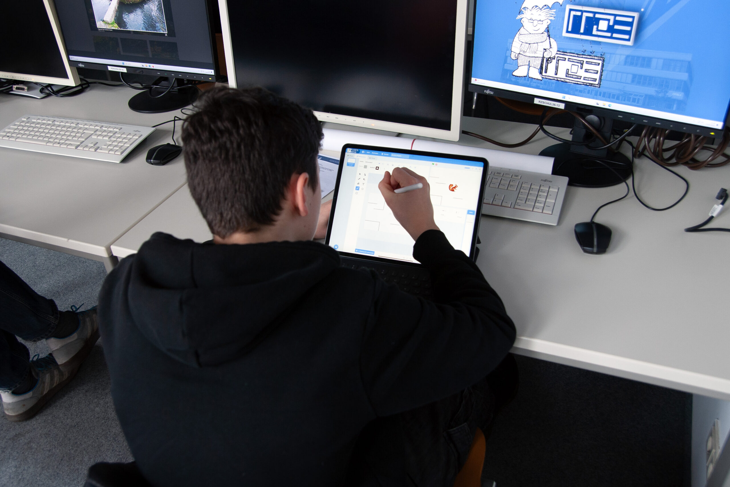 Ein junger Mann sitzt an einem iPad und erstellt mit Scratch ein Labyrinth für ein Pacman-ähnliches Spiel.